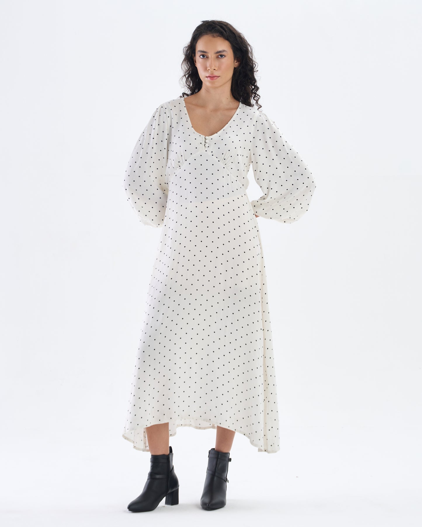 Woman wearing a white dress with black polka dots on a white background