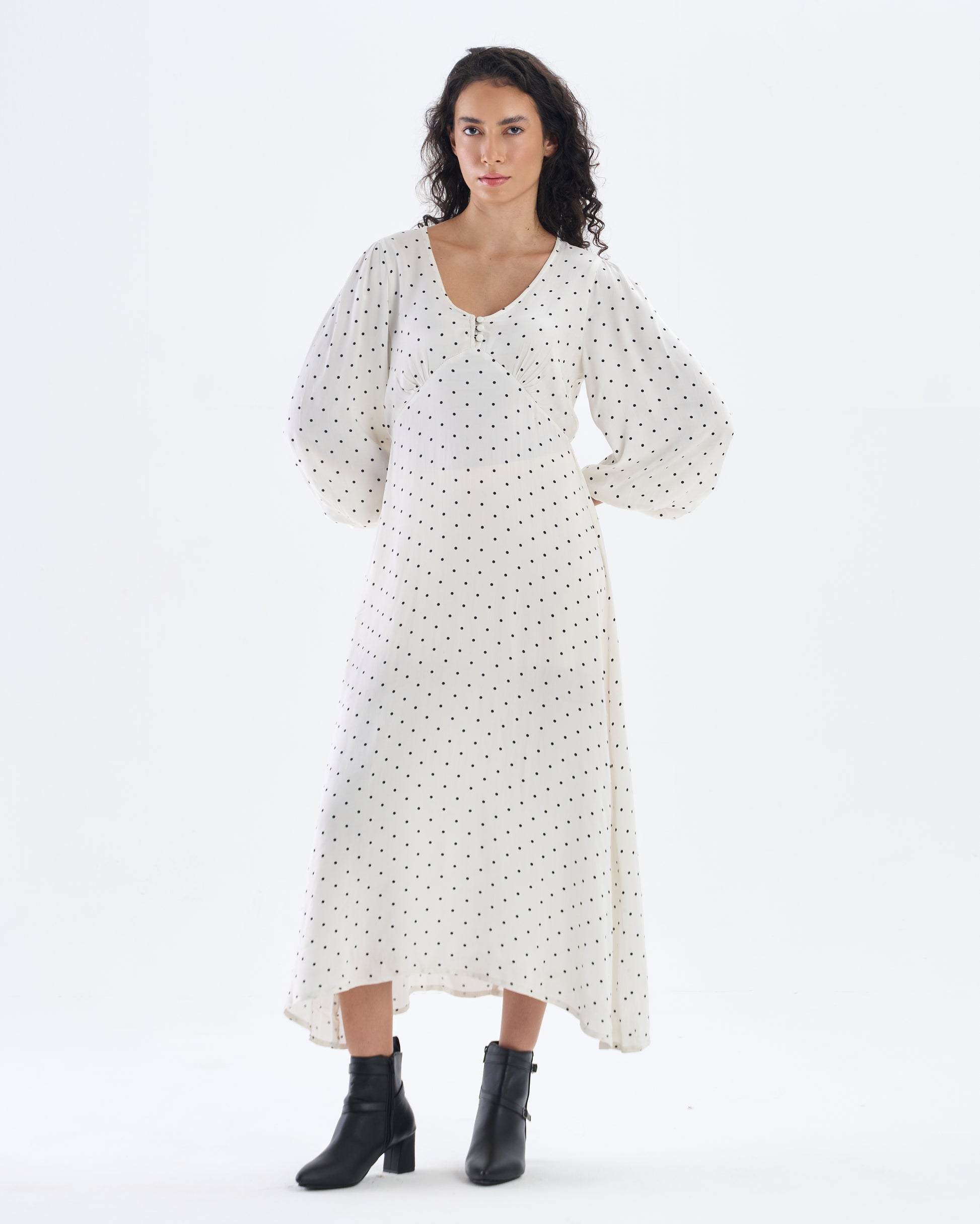 Woman wearing a white dress with black polka dots on a white background